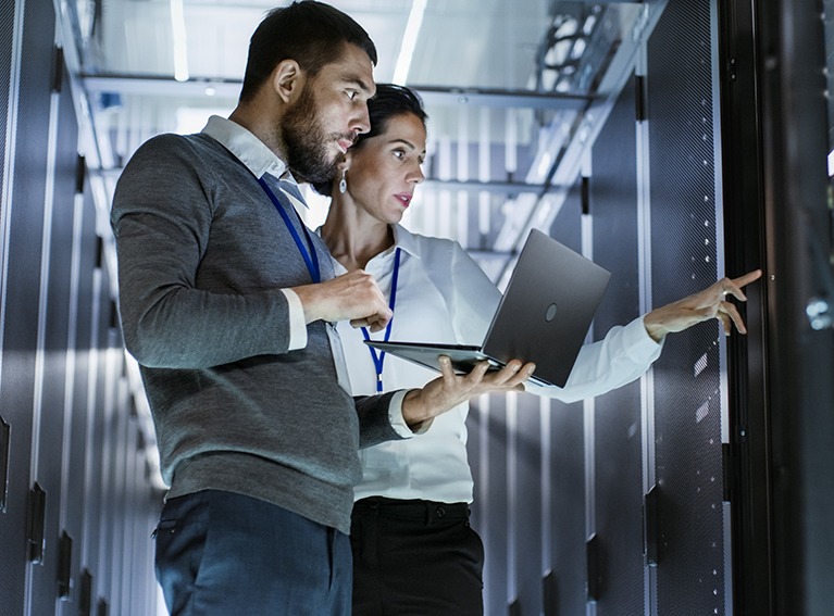 Male-IT-Specialist-Holds-Laptop-and-Discusses-Work-with-Female-Server-Technician